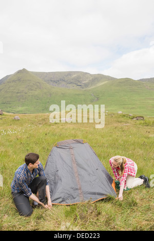 Smiling couple pitching their tent Stock Photo