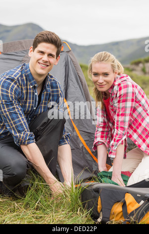 Happy couple pitching their tent together Stock Photo