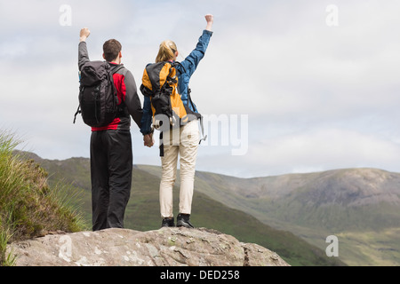 Excited couple reaching the top of their hike and cheering Stock Photo