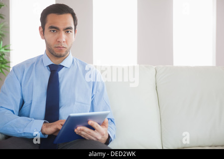 Unsmiling classy businessman using tablet pc Stock Photo