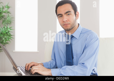 Serious classy businessman using his laptop while sitting on cosy sofa Stock Photo