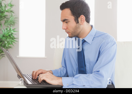 Concentrated businessman using his laptop while sitting on cosy sofa Stock Photo
