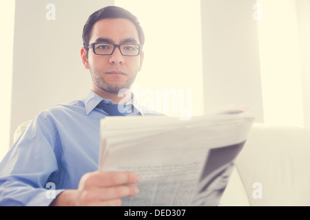 Frowning man looking at camera and holding a newspaper Stock Photo