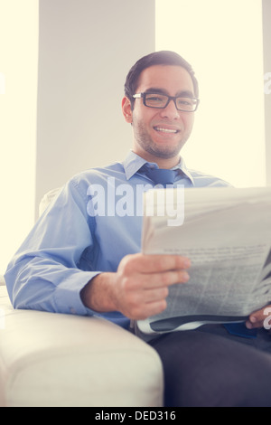 Content man looking and holding a newspaper sitting on sofa Stock Photo