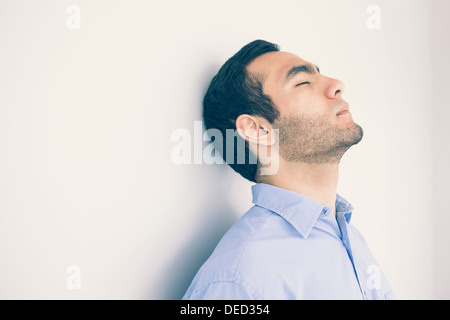 Thoughtful man leaning against a wall Stock Photo