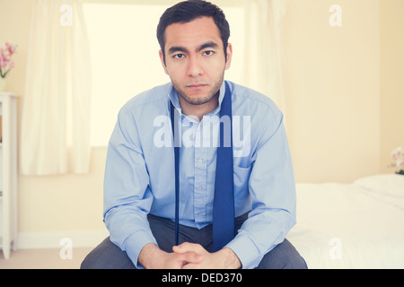 Serious man sitting on his bed Stock Photo