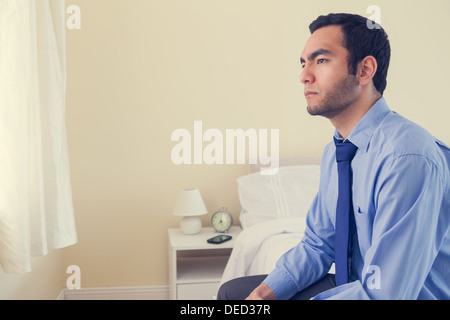 Unhappy man looking away sitting on his bed Stock Photo
