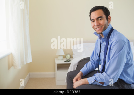 Pleased man looking and relaxing sitting on his bed Stock Photo