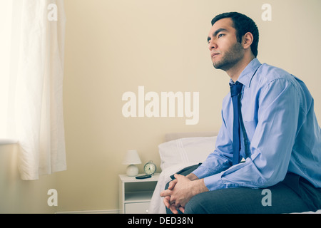 Thinking man looking away sitting on his bed Stock Photo