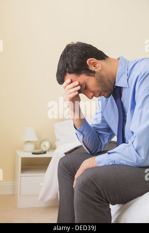 Upset man sitting head in hands on his bed Stock Photo