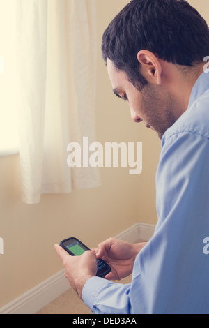 Close up of a man using a mobile phone sitting on a bed Stock Photo