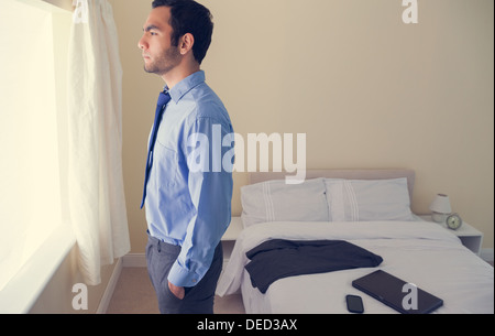 Frowning man standing looking out the window Stock Photo