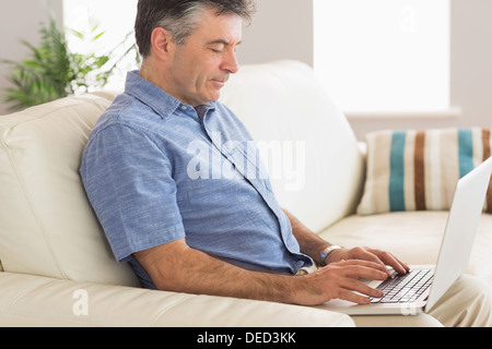 Thinking man sitting on sofa using laptop Stock Photo