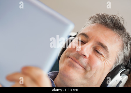 Smiling man listening music and using a tablet pc Stock Photo