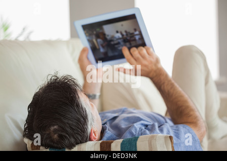 Man laying on a sofa using a tablet pc Stock Photo