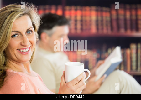 Happy couple reading and drinking coffee in a reading room Stock Photo