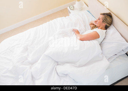 Smiling woman lying on her bed Stock Photo