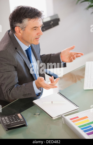 A businessman sitting at his desk explaining something Stock Photo