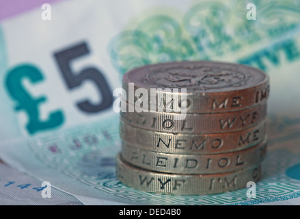 British Sterling Pound coins stacked spelled 'Money', sitting on a UK Fiver Stock Photo