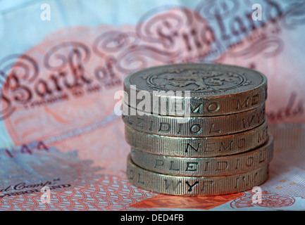 British Sterling Pound coins stacked spelling 'Money' sitting on a UK £10 note Stock Photo