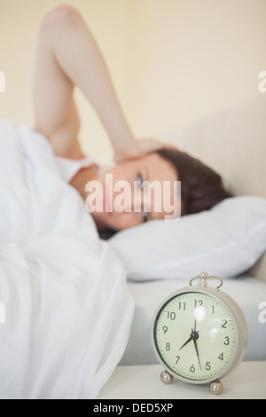 Girl waking in her bed with an alarm clock on foreground Stock Photo