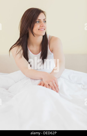 Awakened girl looking away and sitting in her bed Stock Photo