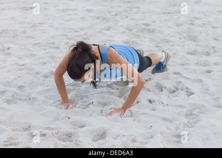 Woman doing push ups at beach Stock Photo