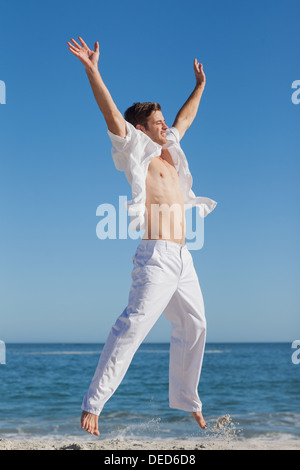 Attractive man jumping on beach Stock Photo