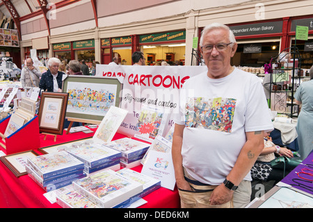 Peter Leech, artist with stall selling cartoon pictures and jigsaws within Newcastle's Grainger Market, north east England, UK Stock Photo