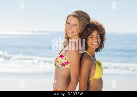 Smiling friends in bikinis standing back-to-back Stock Photo