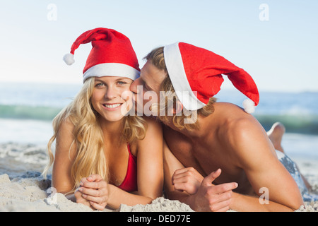 Man giving kiss to partner wearing christmas hats Stock Photo