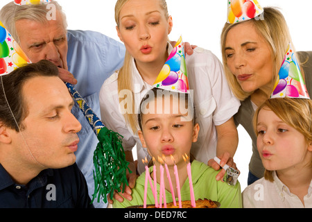 family celebrating birthday party with cake blowing candels Stock Photo