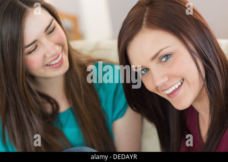 Two laughing friends sitting on the couch with one smiling Stock Photo