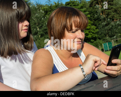 daughter watching her mature mother using a phone Stock Photo