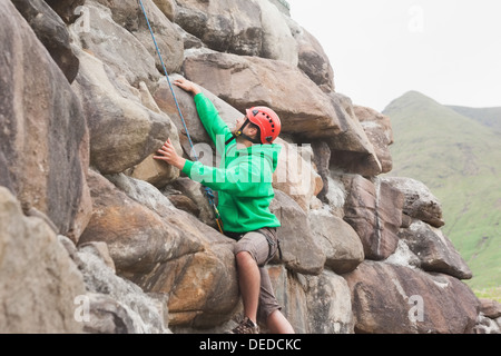 Fit man scaling a large rock face