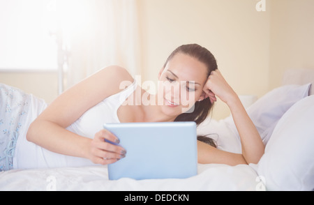 Content brunette lying on bed using her tablet pc Stock Photo