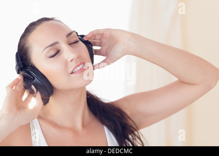 Relaxed brunette sitting on bed listening to music Stock Photo