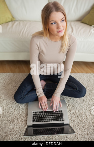 Thoughtful woman sitting on floor using laptop Stock Photo