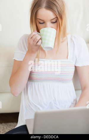 Woman drinking coffee while using laptop Stock Photo