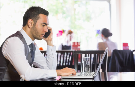 Serious businessman man calling on phone using laptop Stock Photo