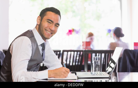 Smiling businessman writing while looking at camera Stock Photo