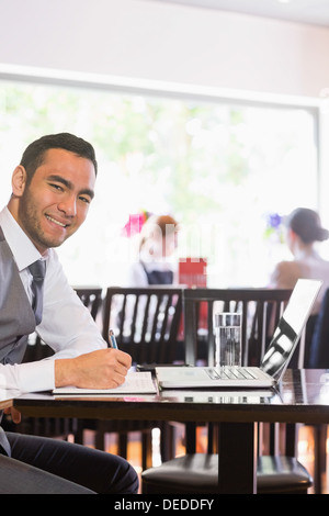 Happy businessman writing while smiling at camera Stock Photo