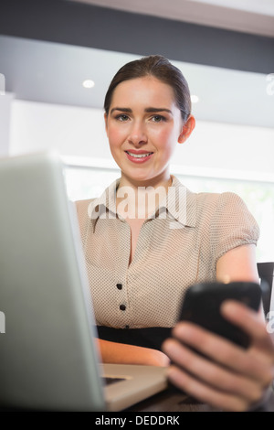 Smiling businesswoman holding her phone in a cafe Stock Photo