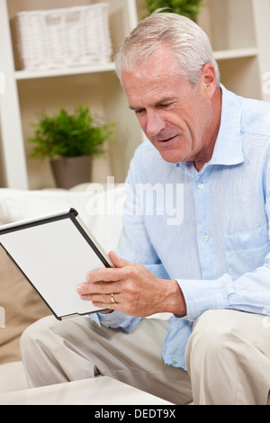 Happy senior man sitting at home using a tablet computer Stock Photo