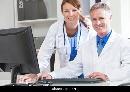 Male & female medical doctors using computer in a hospital office Stock Photo
