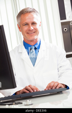 Male medical doctor using computer in his hospital office Stock Photo