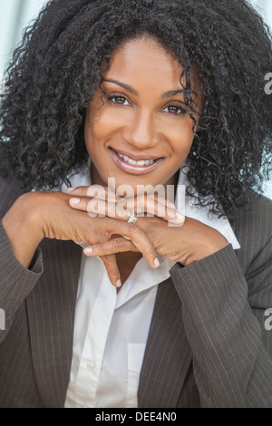 Portrait of a beautiful middle aged African American woman or businesswoman sitting relaxing & smiling Stock Photo