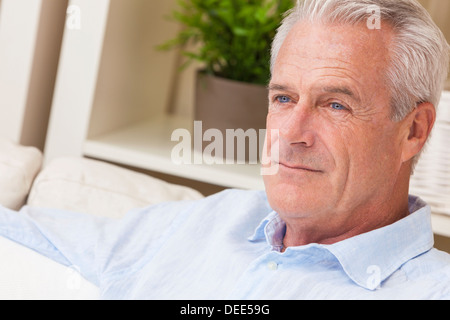Happy and healthy senior man sitting on a sofa at home thoughtful and happy Stock Photo