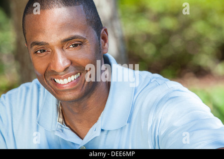 A happy African American man sitting outside and smiling with perfect white teeth Stock Photo