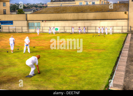 Women playing bowls summer day with blue sky and white clouds in HDR, English game played on green lawn Stock Photo